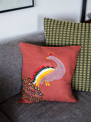 Peacock pillow on red linen
