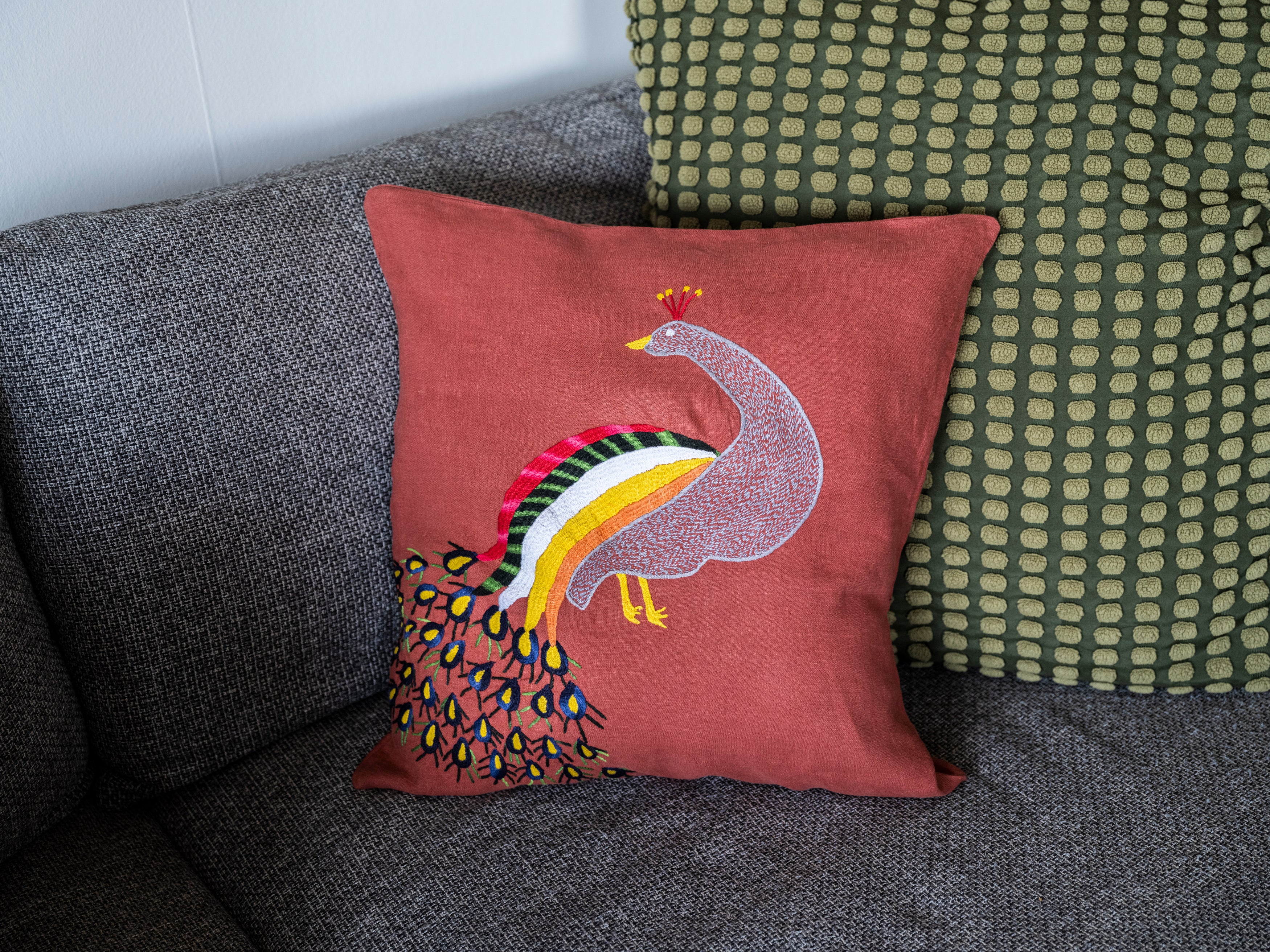 Peacock pillow on red linen