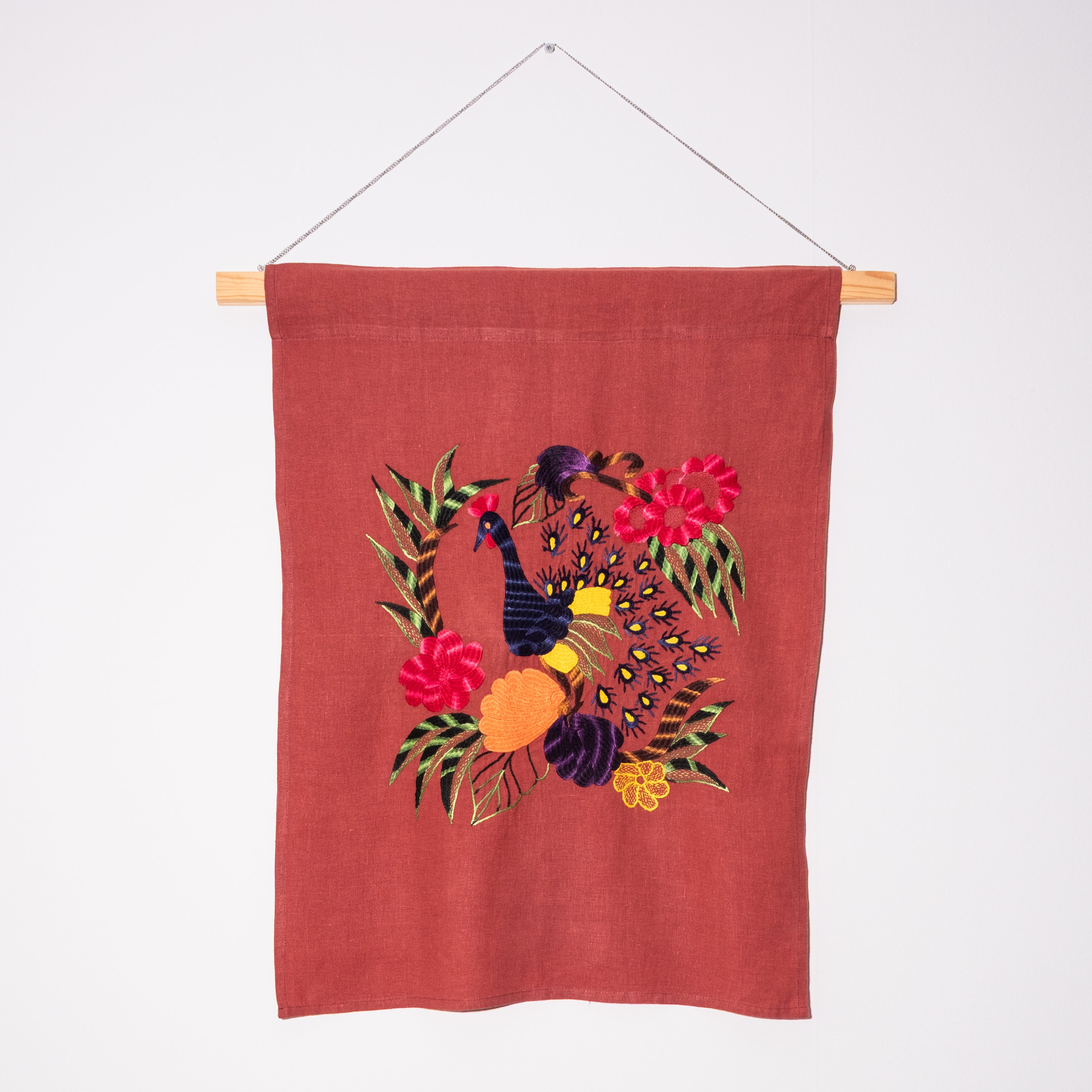 Peacock wall hanging on red linen