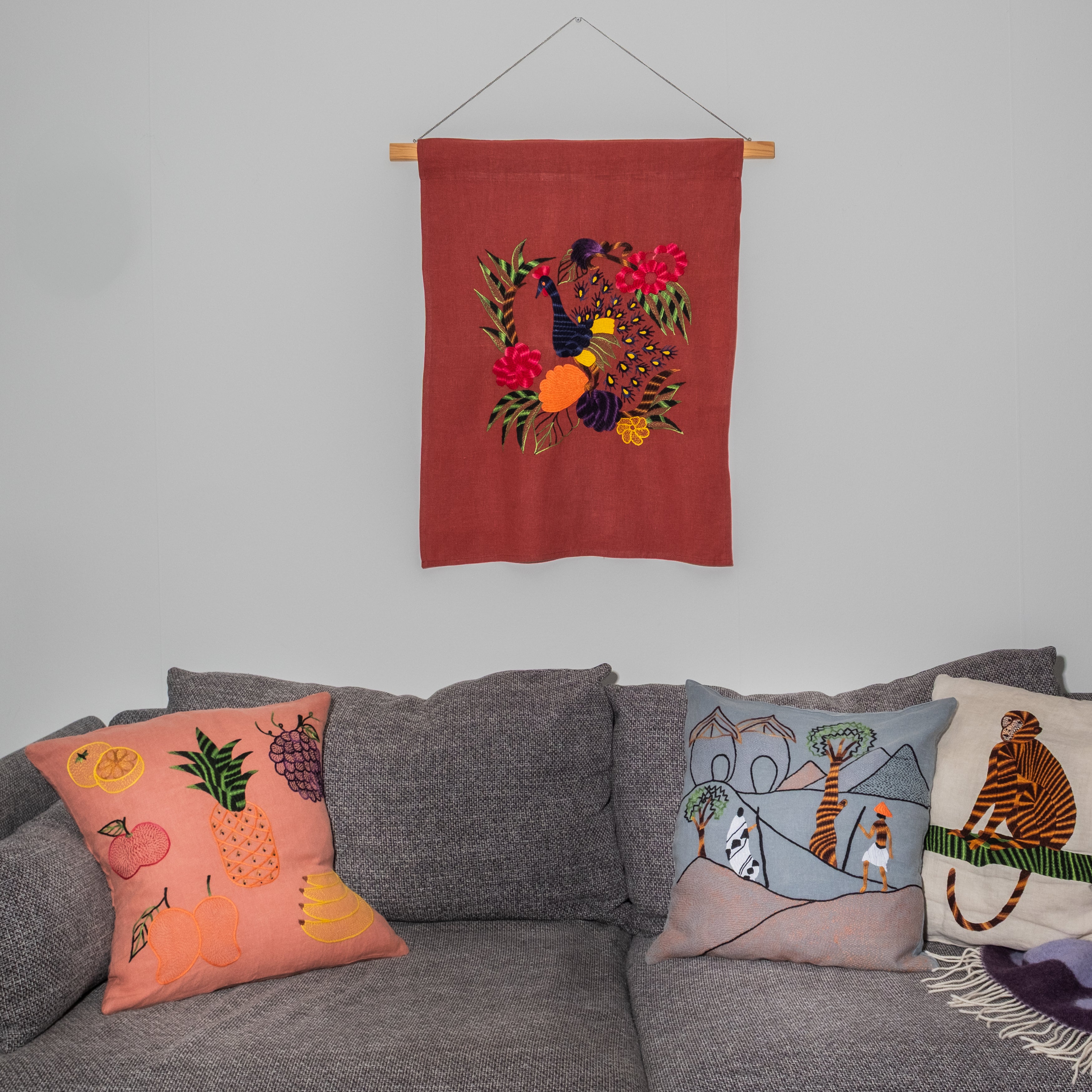Peacock wall hanging on red linen