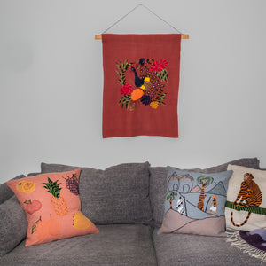 Peacock wall hanging on red linen